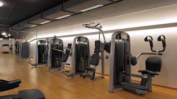 Une salle de sport équipée de divers appareils d’exercice et de bancs.