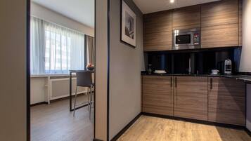 A modern kitchen with wooden cabinets, a microwave, and a coffee machine.