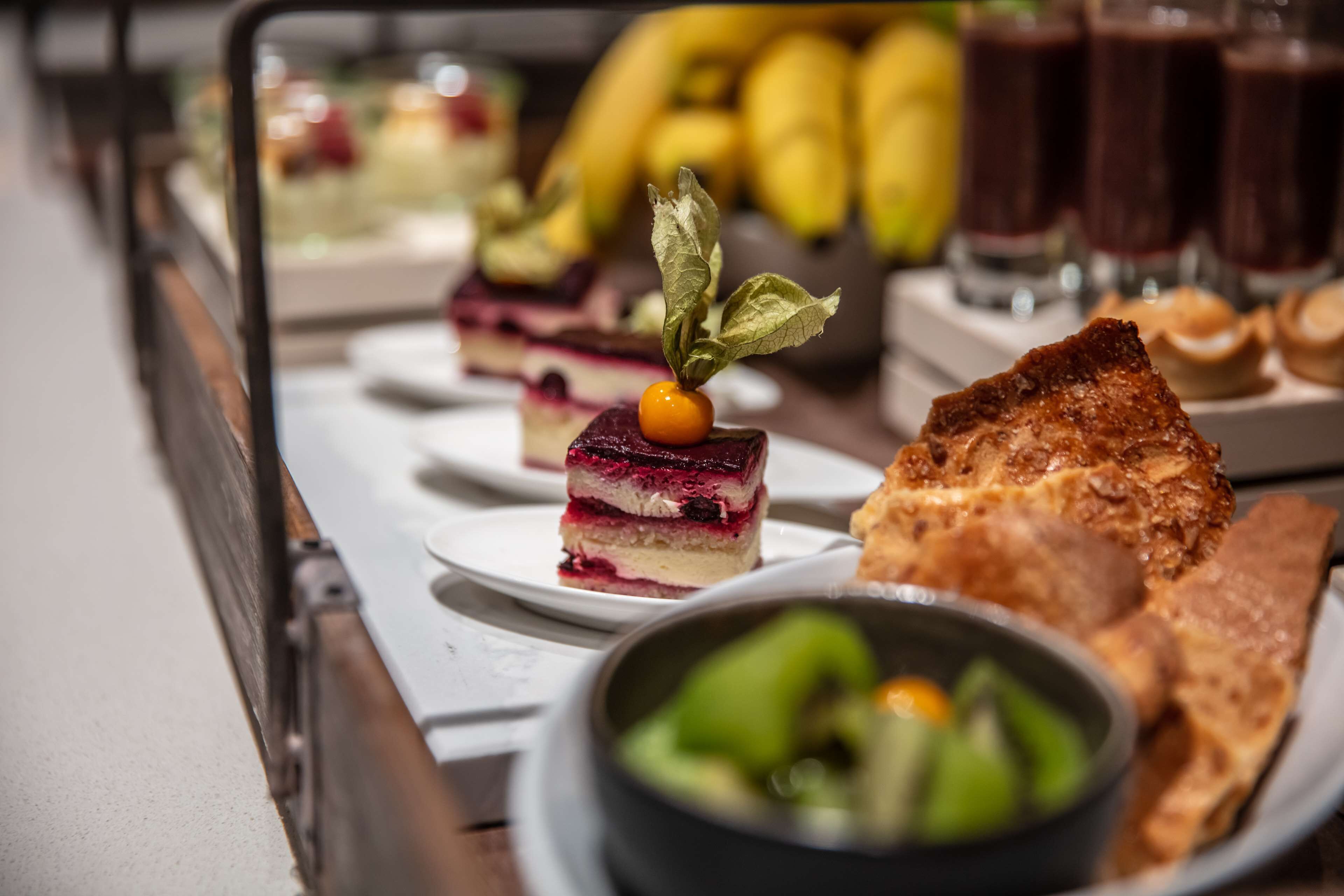 A dessert table with various sweet treats and a bowl of green vegetables.