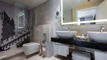 A modern bathroom with a large mirror, two sinks, and a toilet.