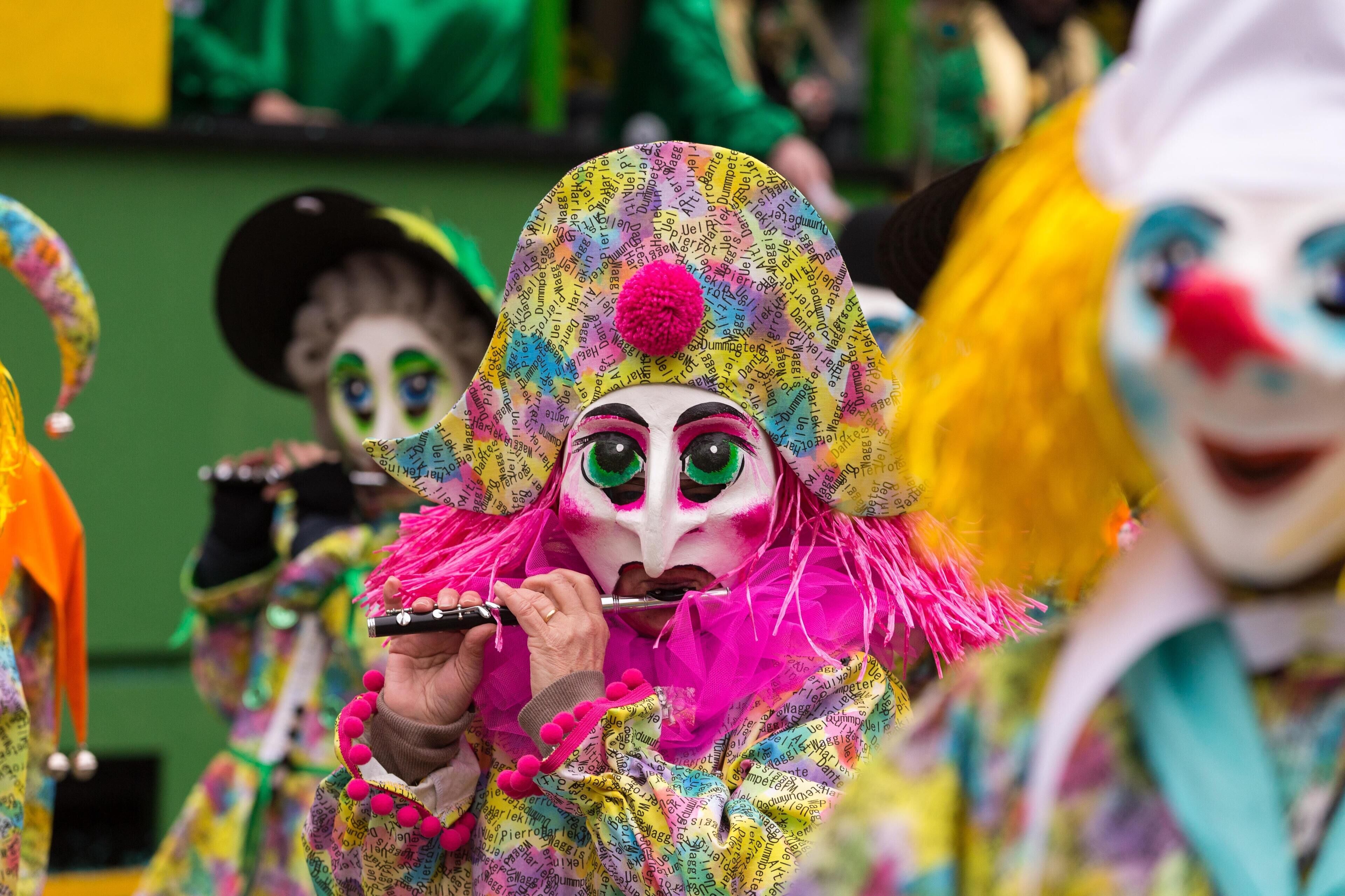 A person in a colorful costume with a mask, holding a small object.