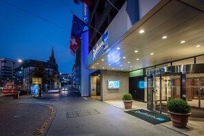 A Radisson Blu hotel entrance with a modern facade, a visible entrance, and a large potted plant in front.