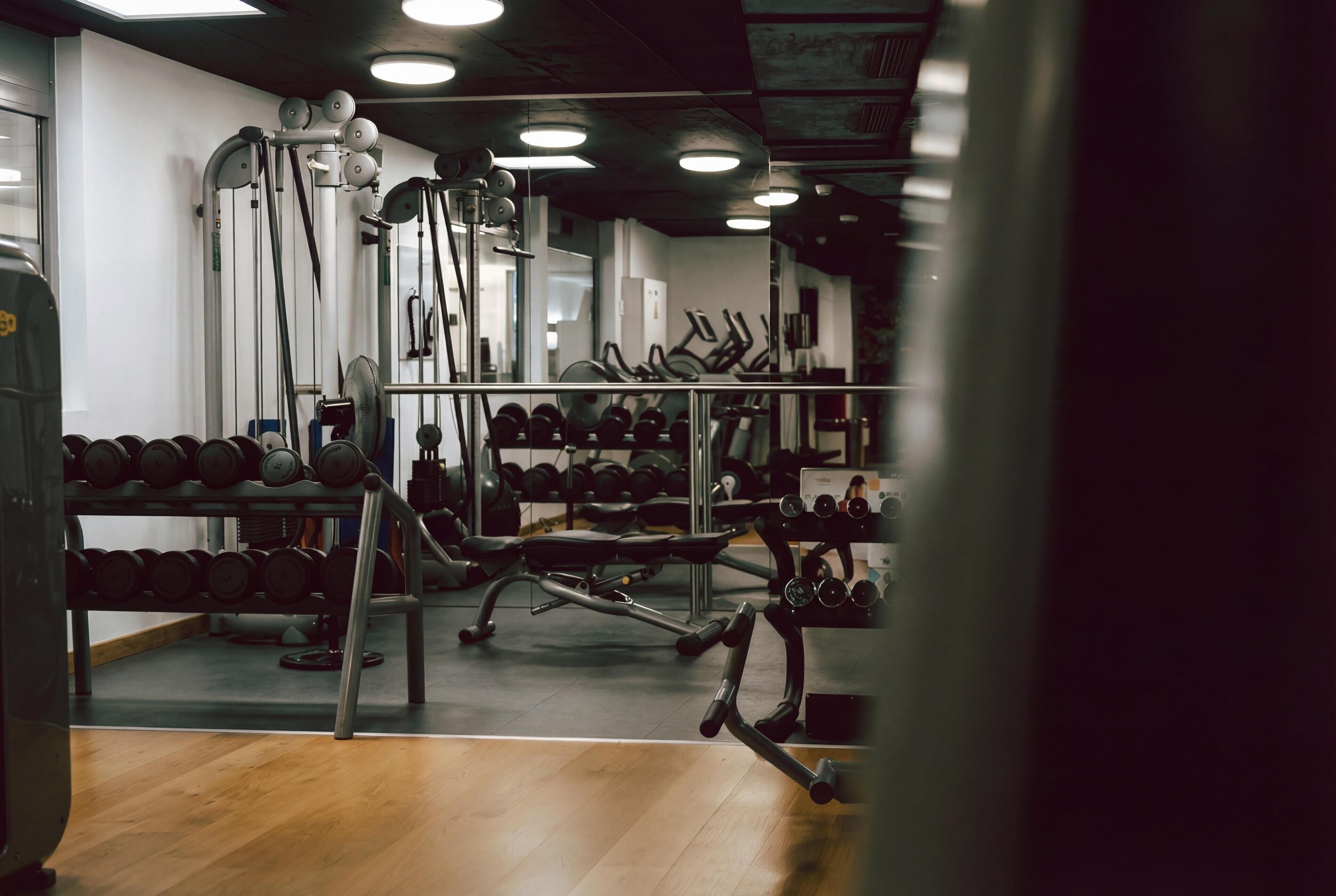Un gimnasio con diverso equipo de ejercicio, como mancuernas, cintas de correr y máquinas de pesas.