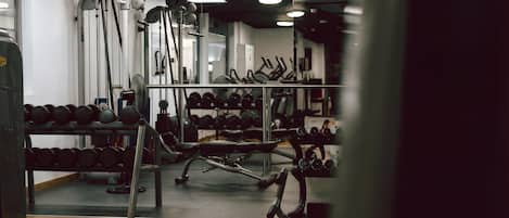 Un gimnasio con diverso equipo de ejercicio, como mancuernas, cintas de correr y máquinas de pesas.