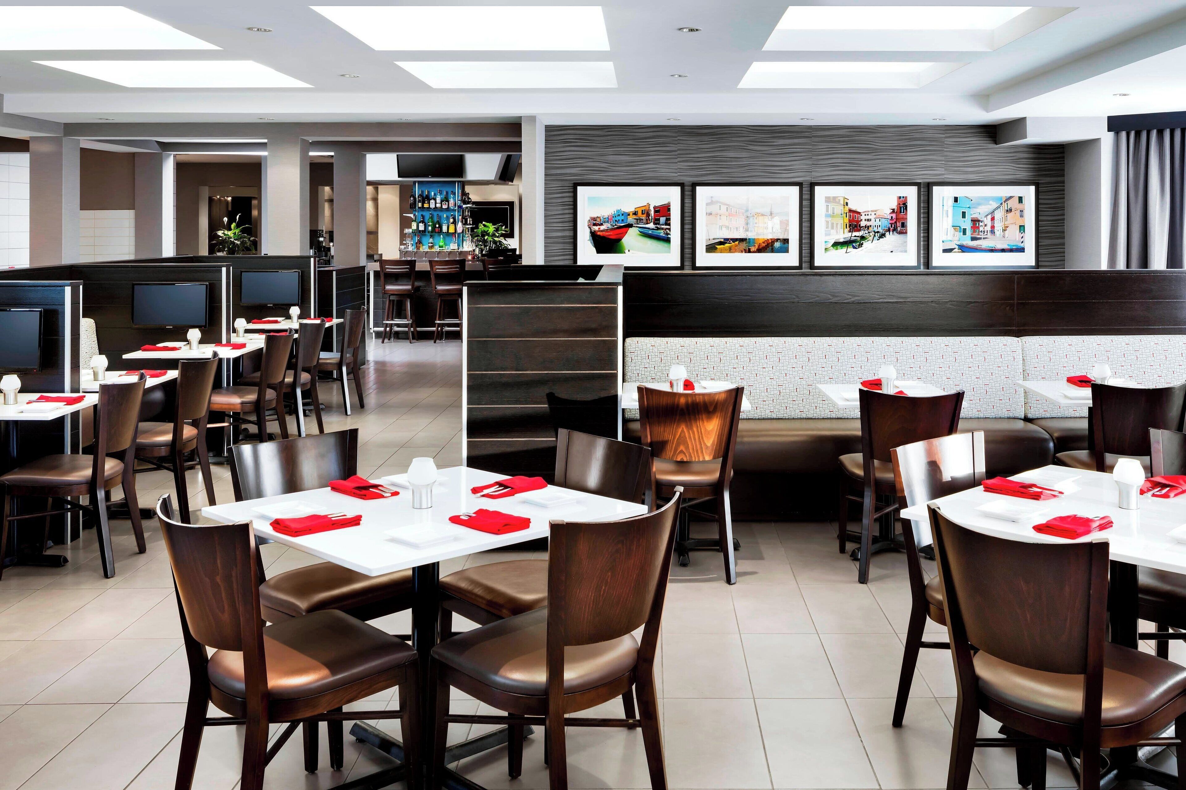 Un restaurante moderno con cabinas y mesas, una zona de bar y obras de arte en las paredes.