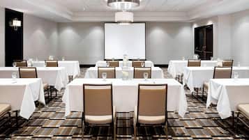 A conference room with multiple tables, chairs, and a projector screen.