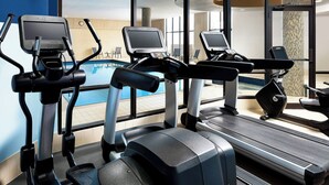 Tres máquinas de ejercicio, una piscina y vistas del área de la piscina.