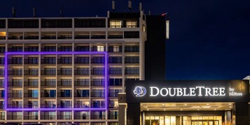 A hotel with multiple floors, a prominent "DOUBLETREE by Hilton" sign, and a purple-lit facade.