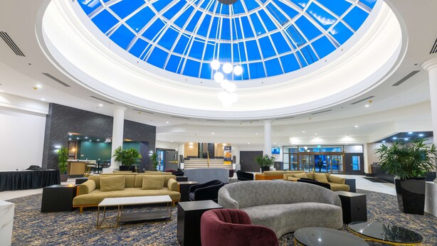 A spacious lobby with a central skylight, comfortable seating areas, and a reception desk. - DoubleTree by Hilton Calgary North (Calgary)