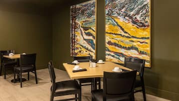 Una sala de conferencias con una mesa de madera, sillas negras y dos grandes pinturas abstractas en las paredes.