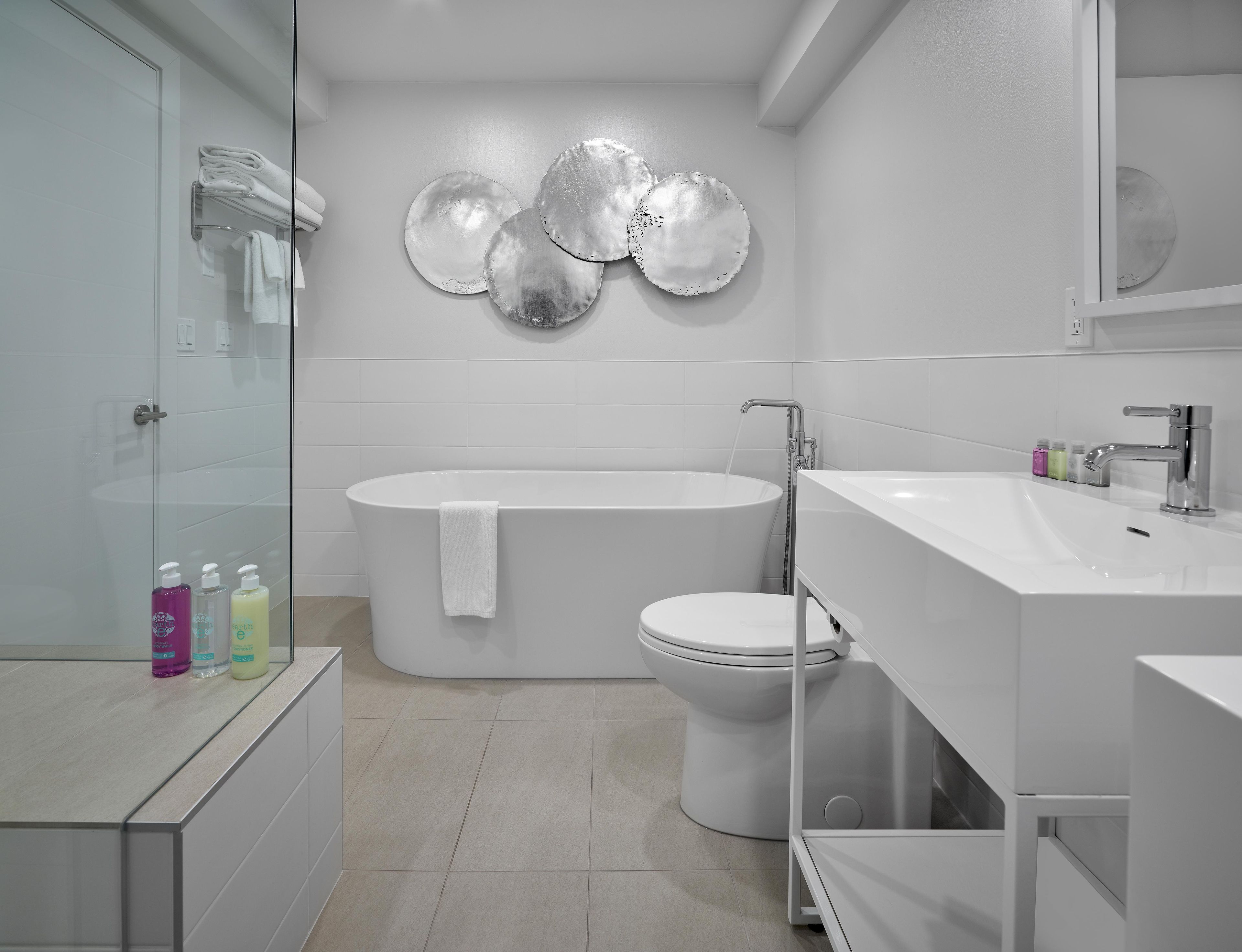A modern bathroom with a freestanding bathtub, a toilet, and a sink with a mirror.