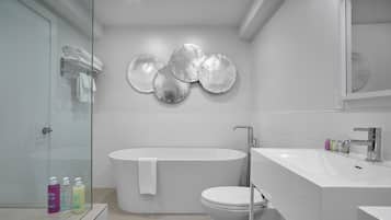 A modern bathroom with a freestanding bathtub, a toilet, and a sink with a mirror.
