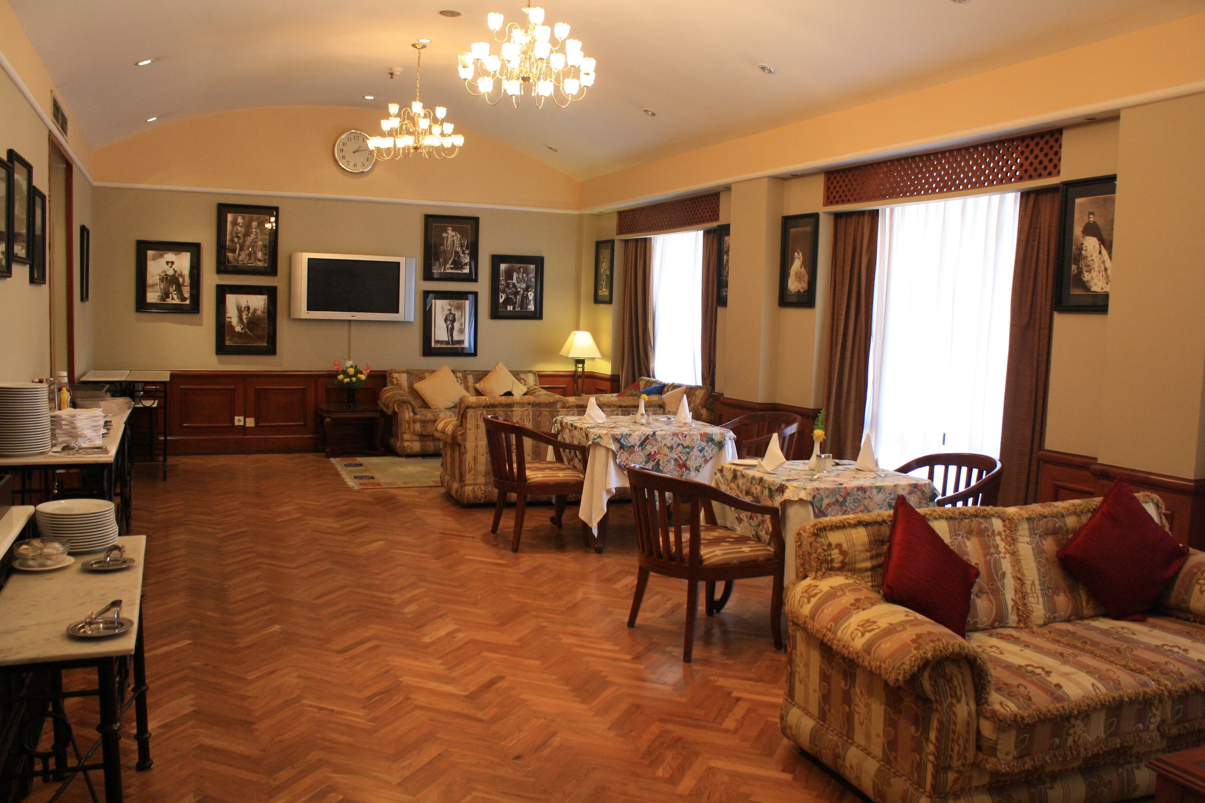 Un salon spacieux doté d’un parquet en point de Hongrie, un coin repas avec une table dressée pour quatre personnes et un canapé agrémenté de coussins rouges.