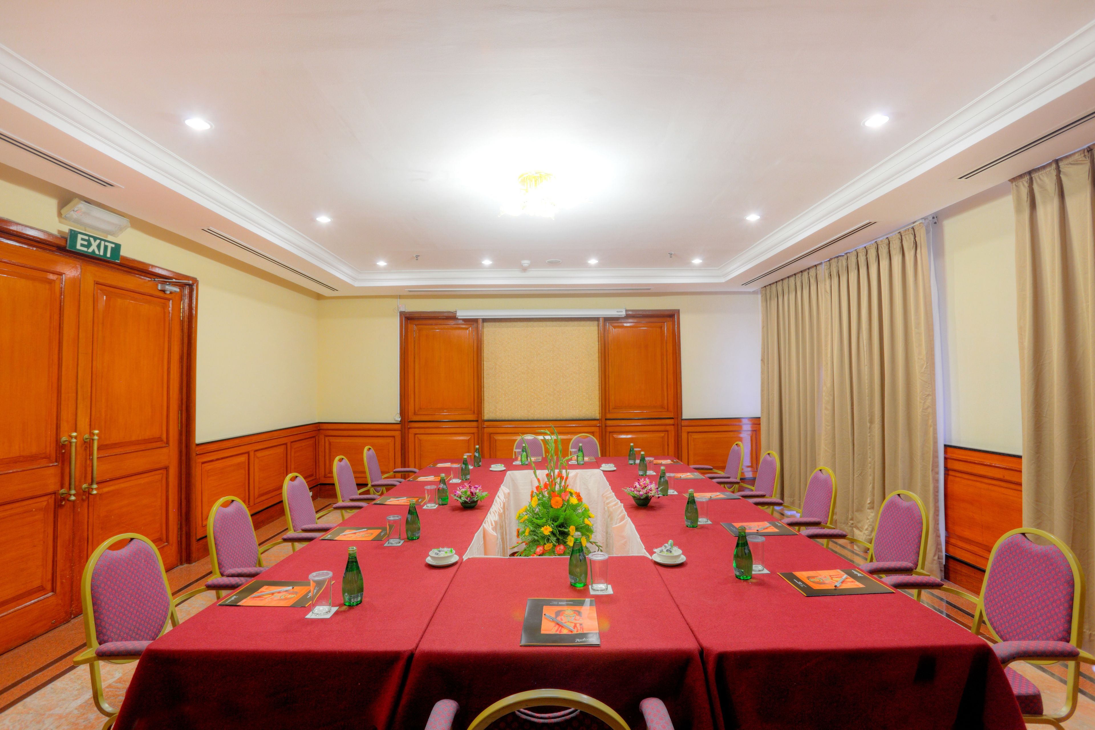 A conference room with a long table, chairs, and a floral centerpiece.