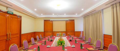 A conference room with a long table, chairs, and a floral centerpiece.