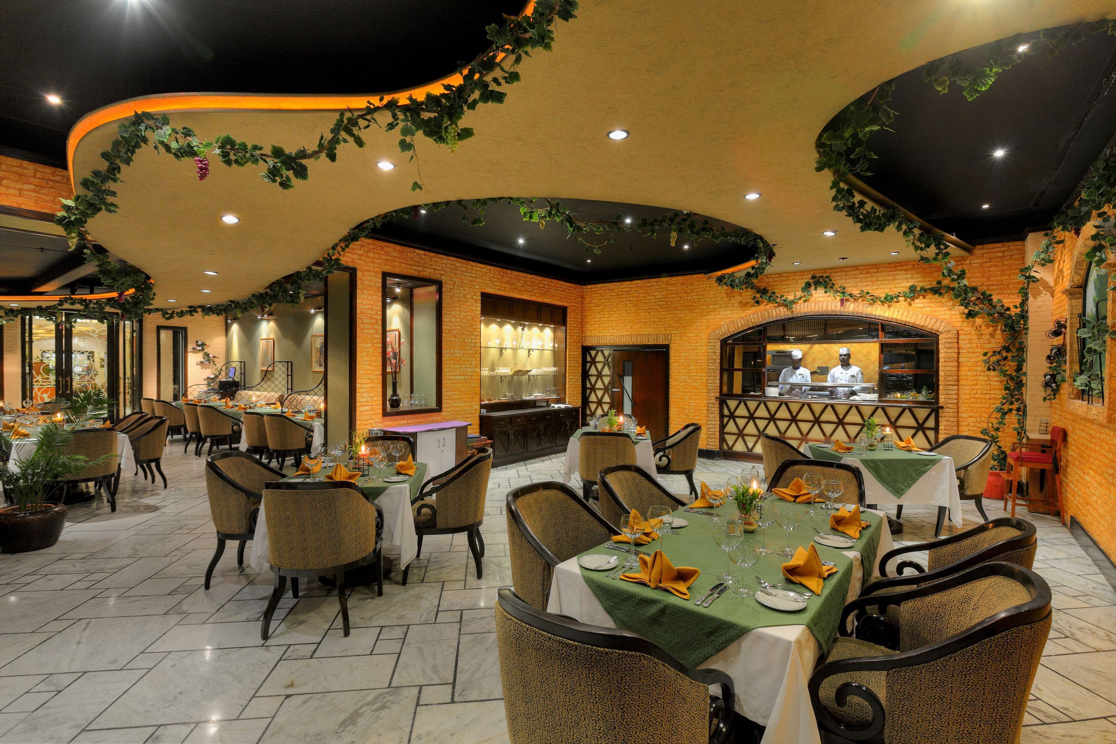 A restaurant with brick walls, green vines, and tables set for dining.