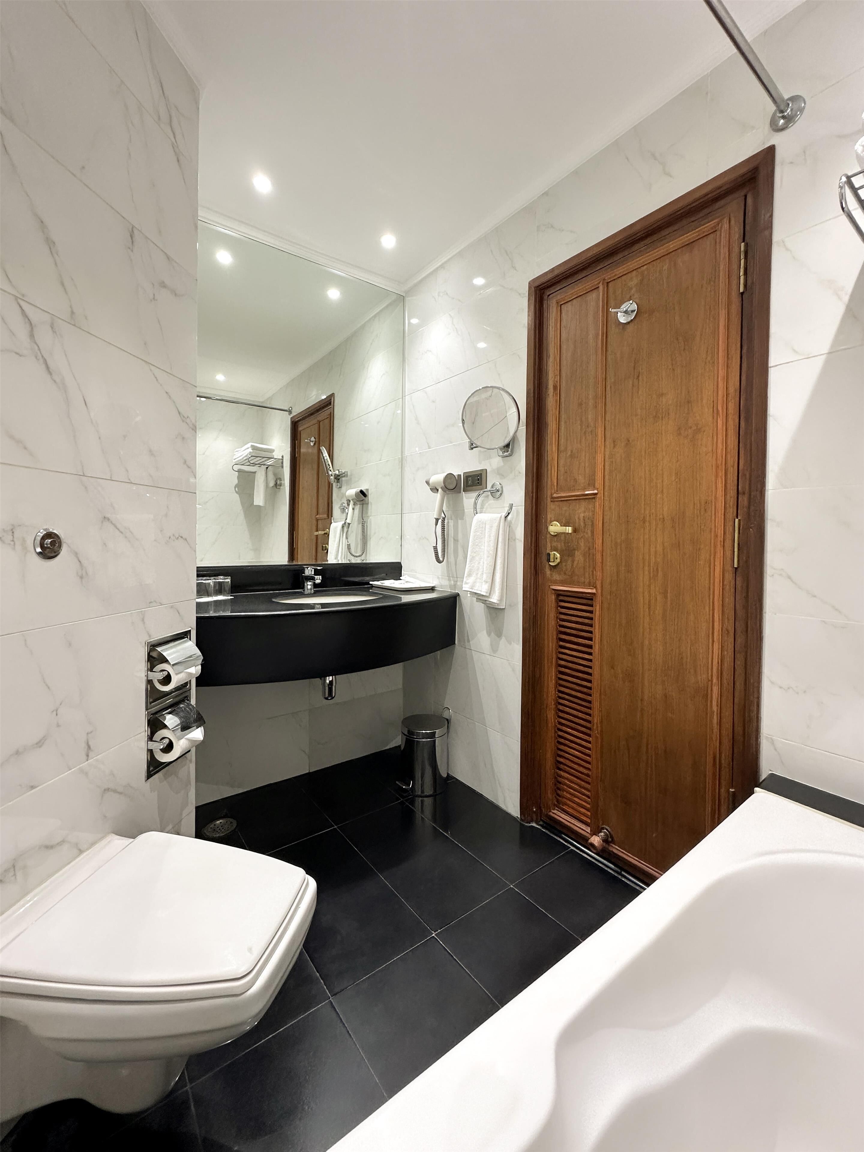 Un baño moderno con un lavabo negro, inodoro blanco y una bañera.