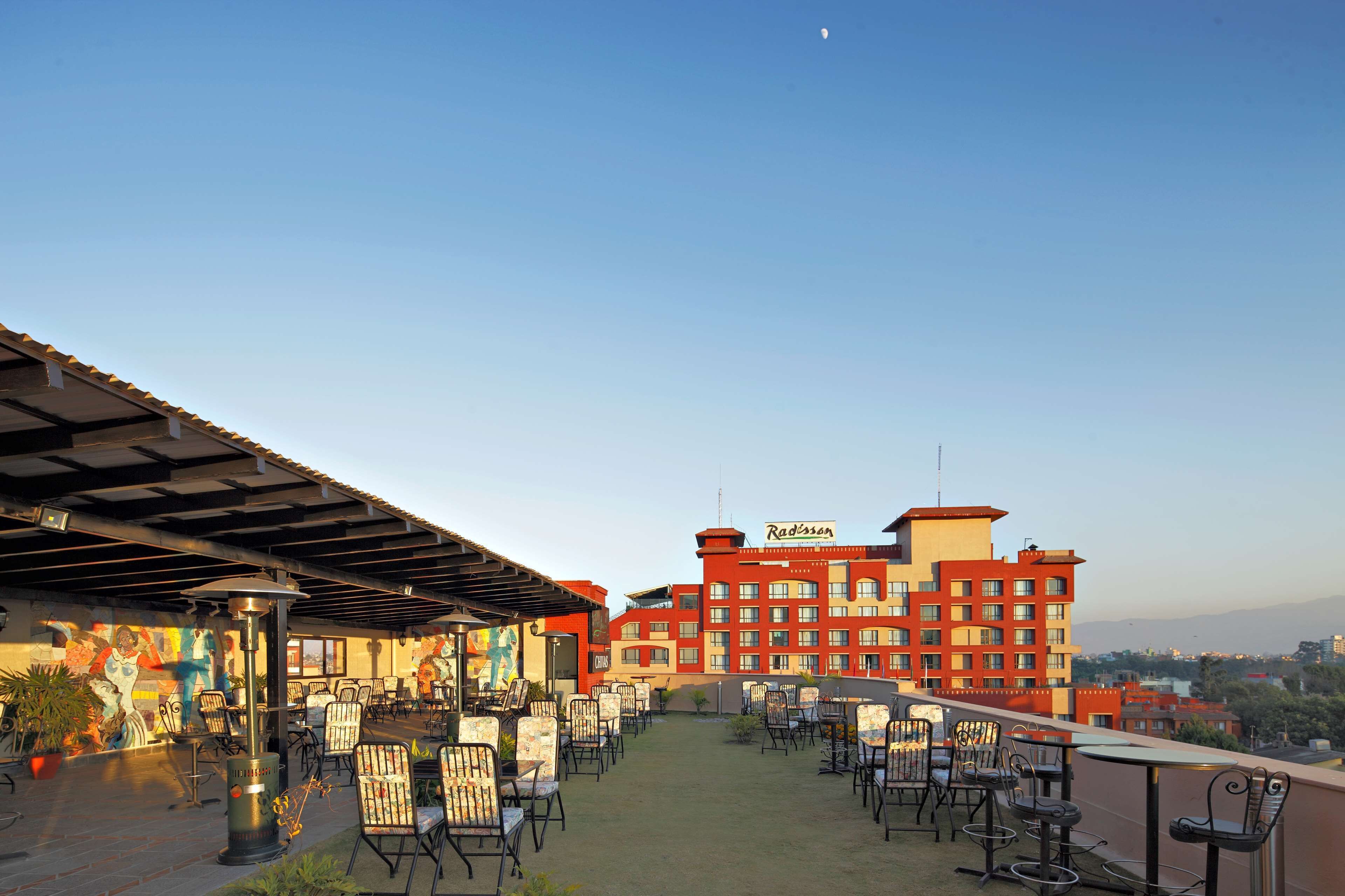 An outdoor seating area with chairs and tables, a mural, and a building with the name "Radisson" in the background.