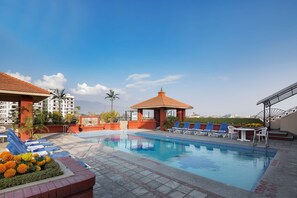 Una piscina al aire libre, sillones reclinables de piscina