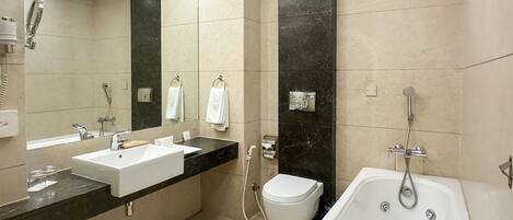 A modern bathroom with a large mirror, a white sink, a bathtub, and a toilet.
