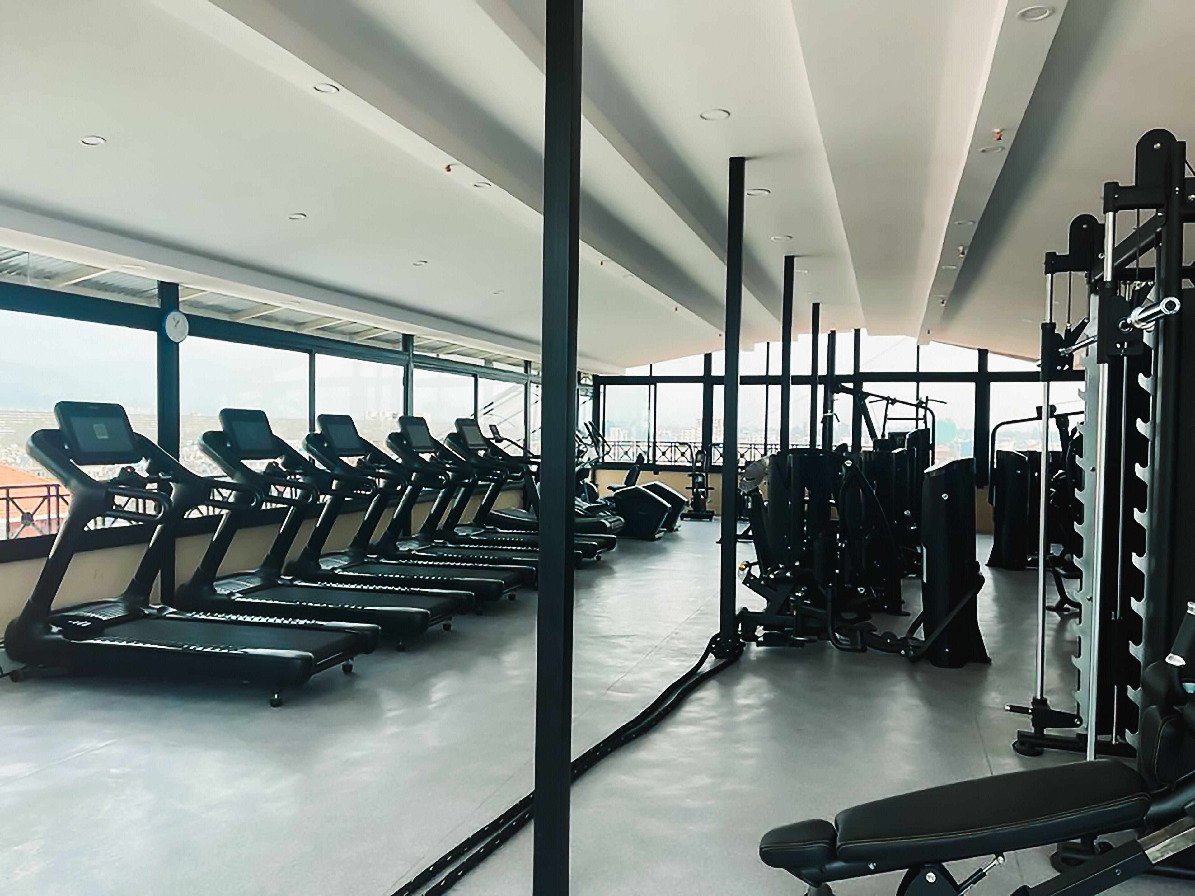 Une salle de sport équipée de tapis de course, d’appareils de musculation et d’un banc.