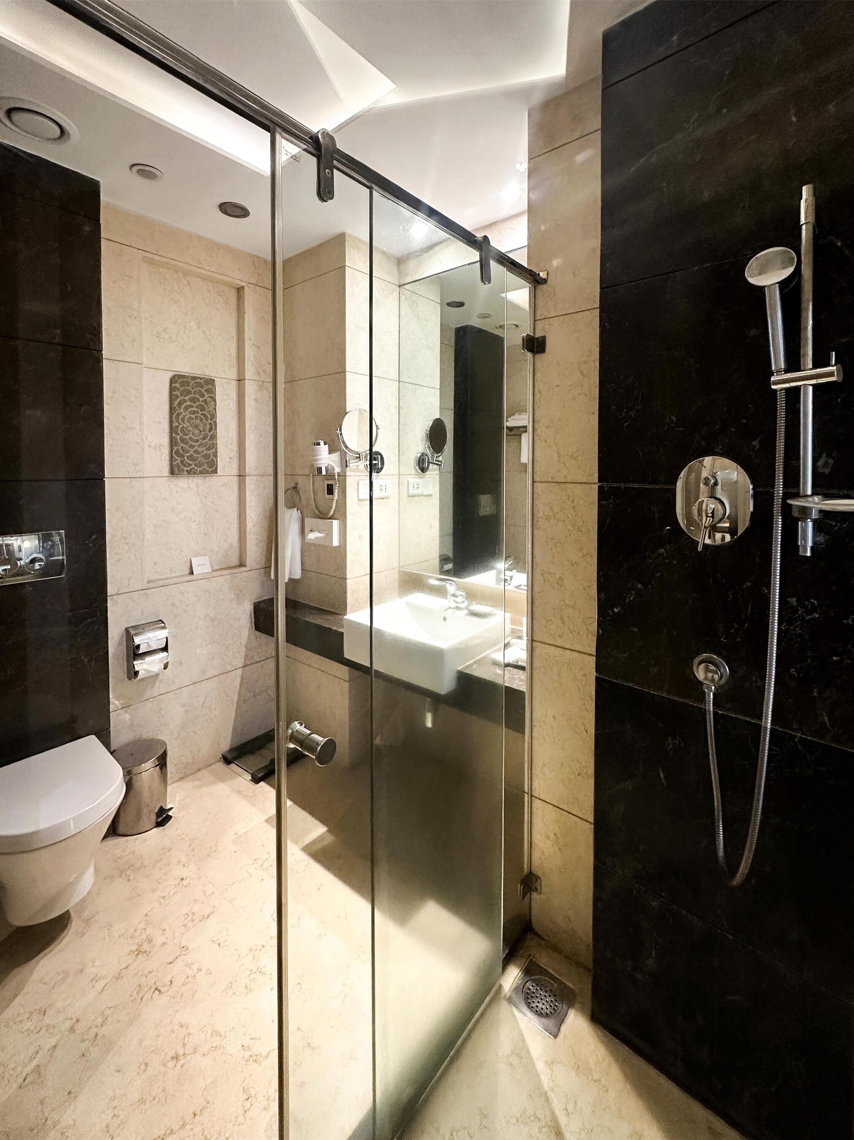 A modern bathroom with a glass-enclosed shower, a white sink, and a toilet.