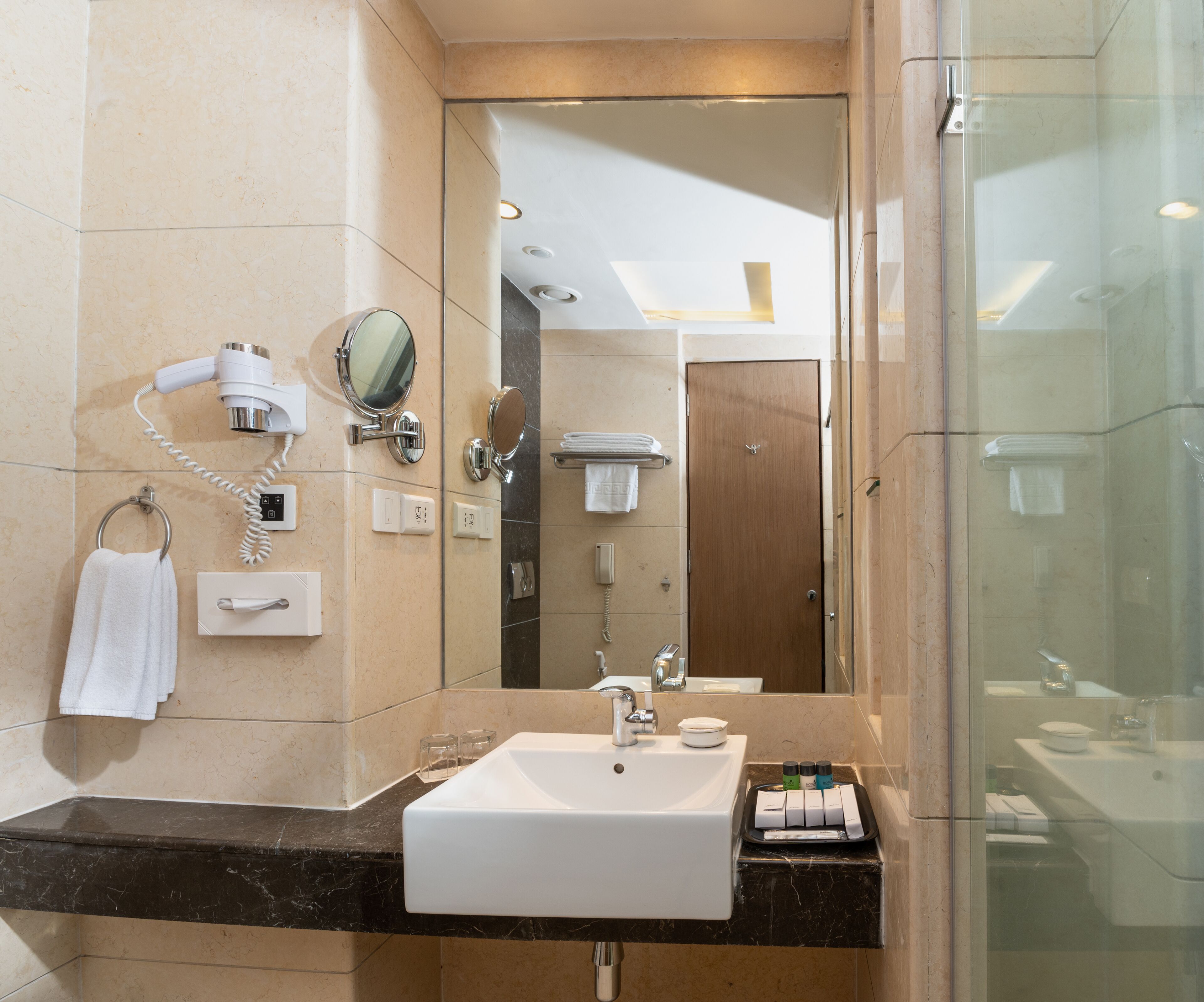 A modern bathroom with a large mirror, a sink, and a hairdryer.