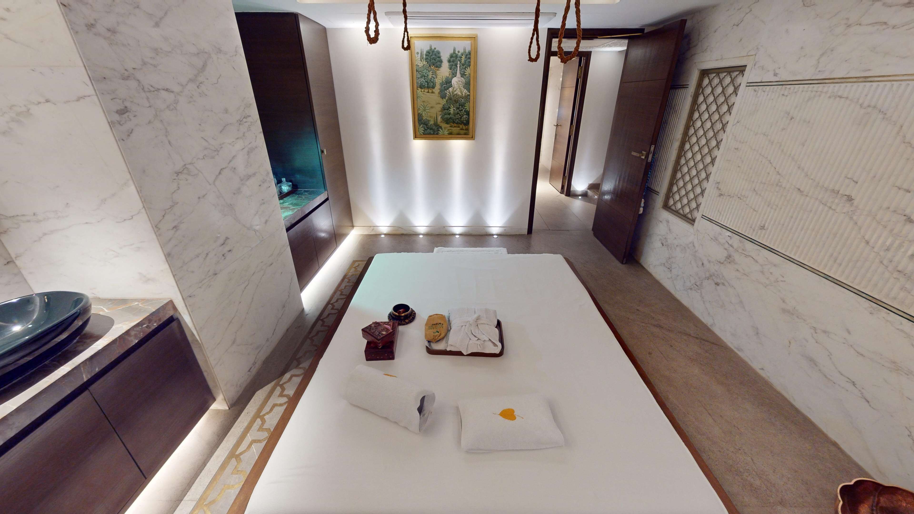 A modern hotel room with a large bed, a small bathroom, and a marble floor.