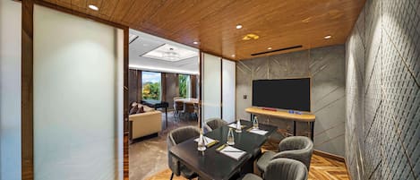 A conference room with a wooden ceiling, a large flat-screen TV, and a herringbone-patterned floor.