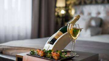 Una botella de champán y una copa sobre una mesa con un plato de aperitivos.