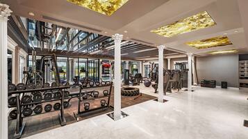 A modern gym with a skylight, weight racks, cardio equipment, and a clean, polished floor.