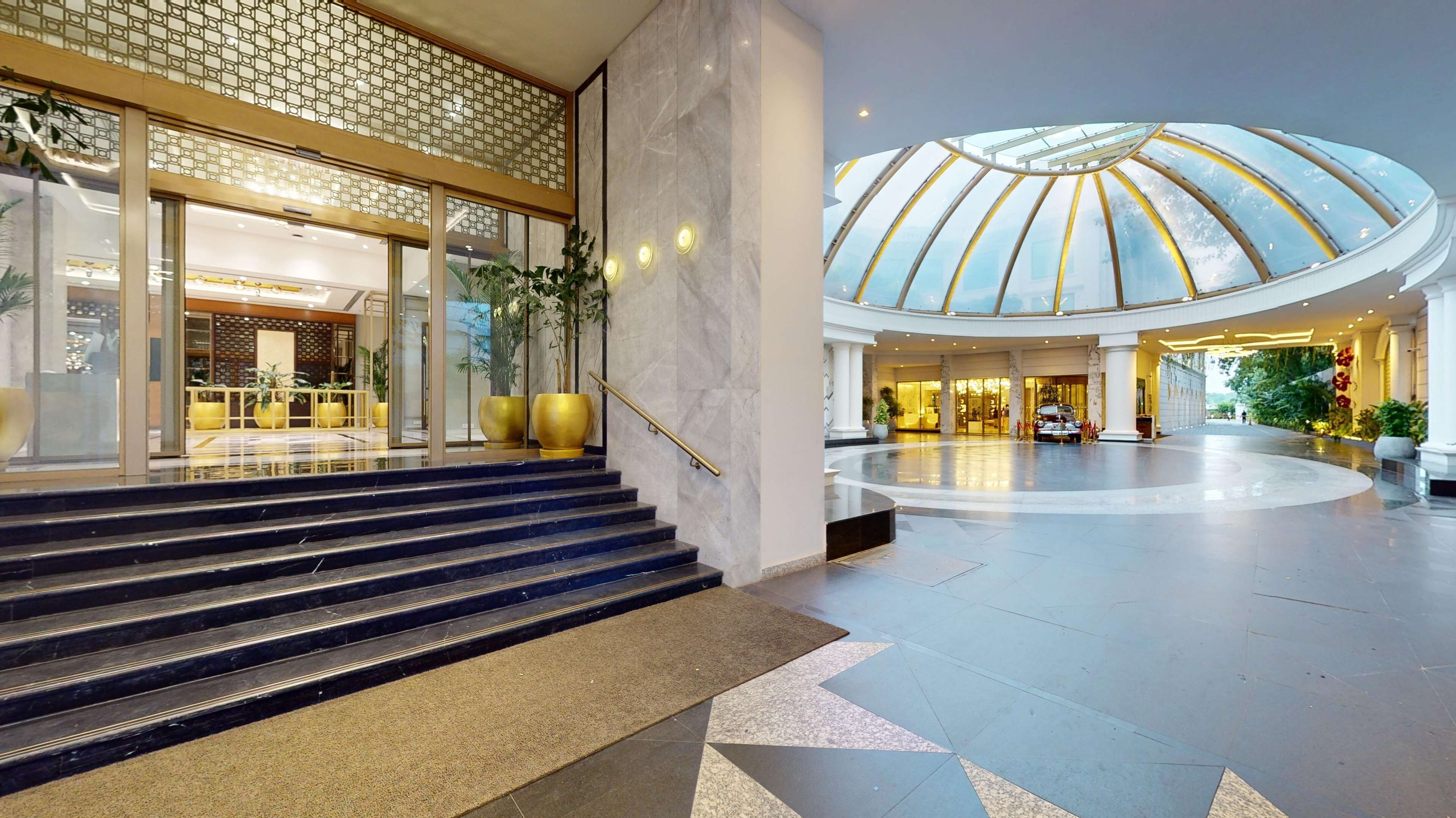 Een hotellobby met een monumentale trap, een glazen plafond en een ruime atrium.