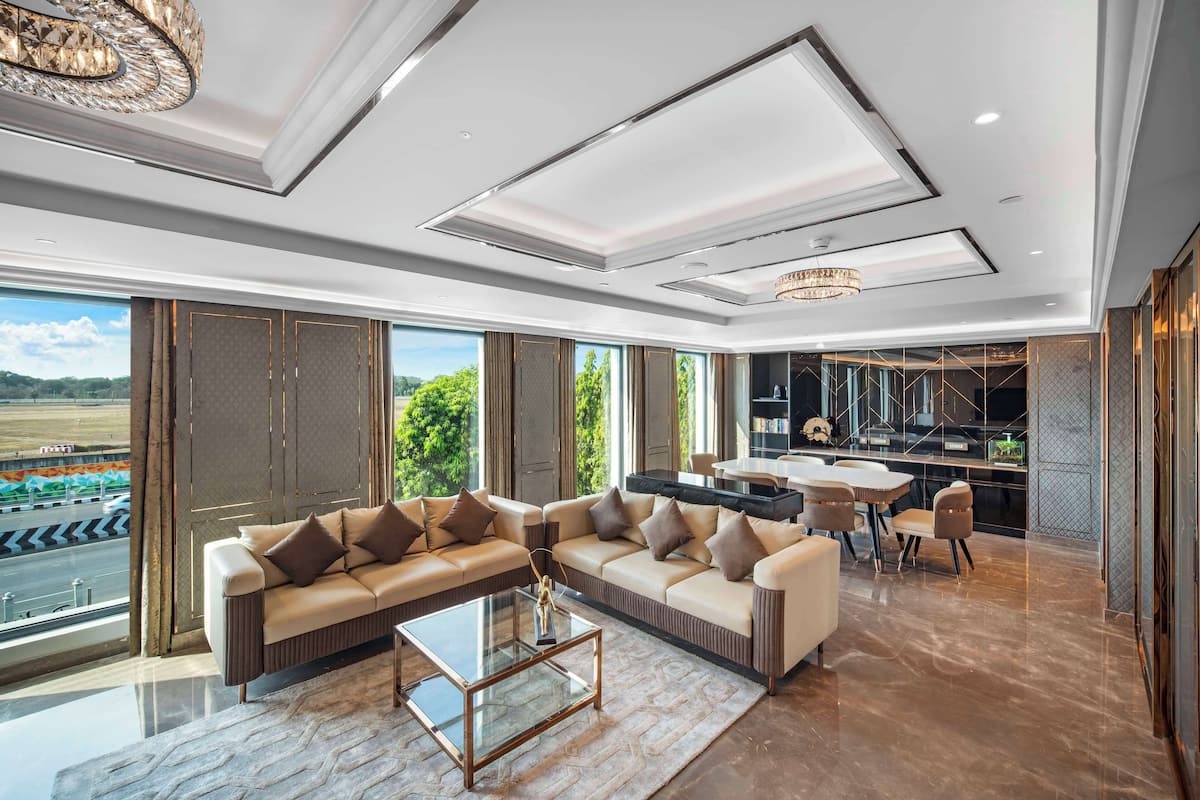 A modern living room with a sectional sofa, a glass coffee table, and a dining area with a table and chairs.