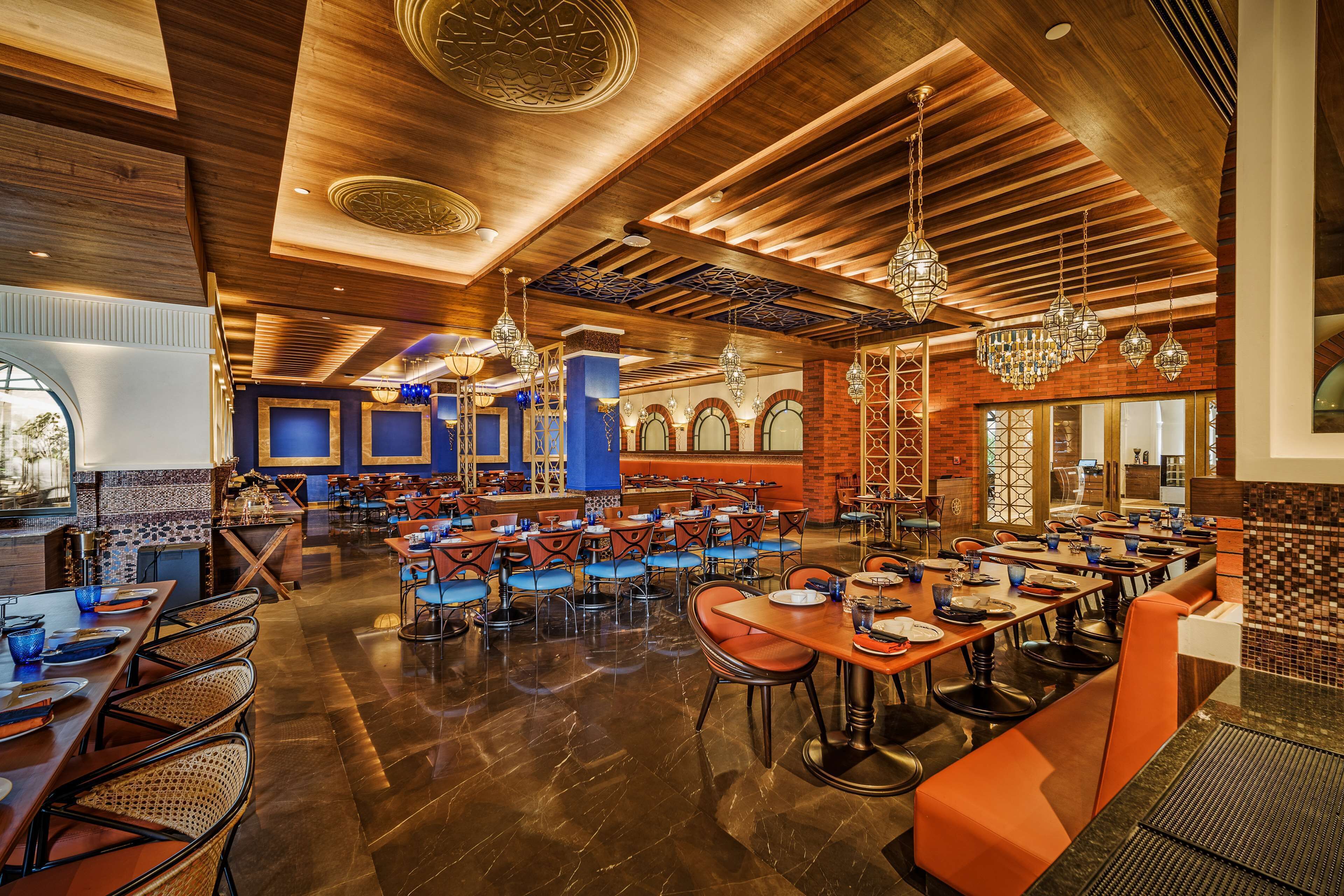 A spacious restaurant with high wooden ceilings, multiple dining areas, and hanging chandeliers.