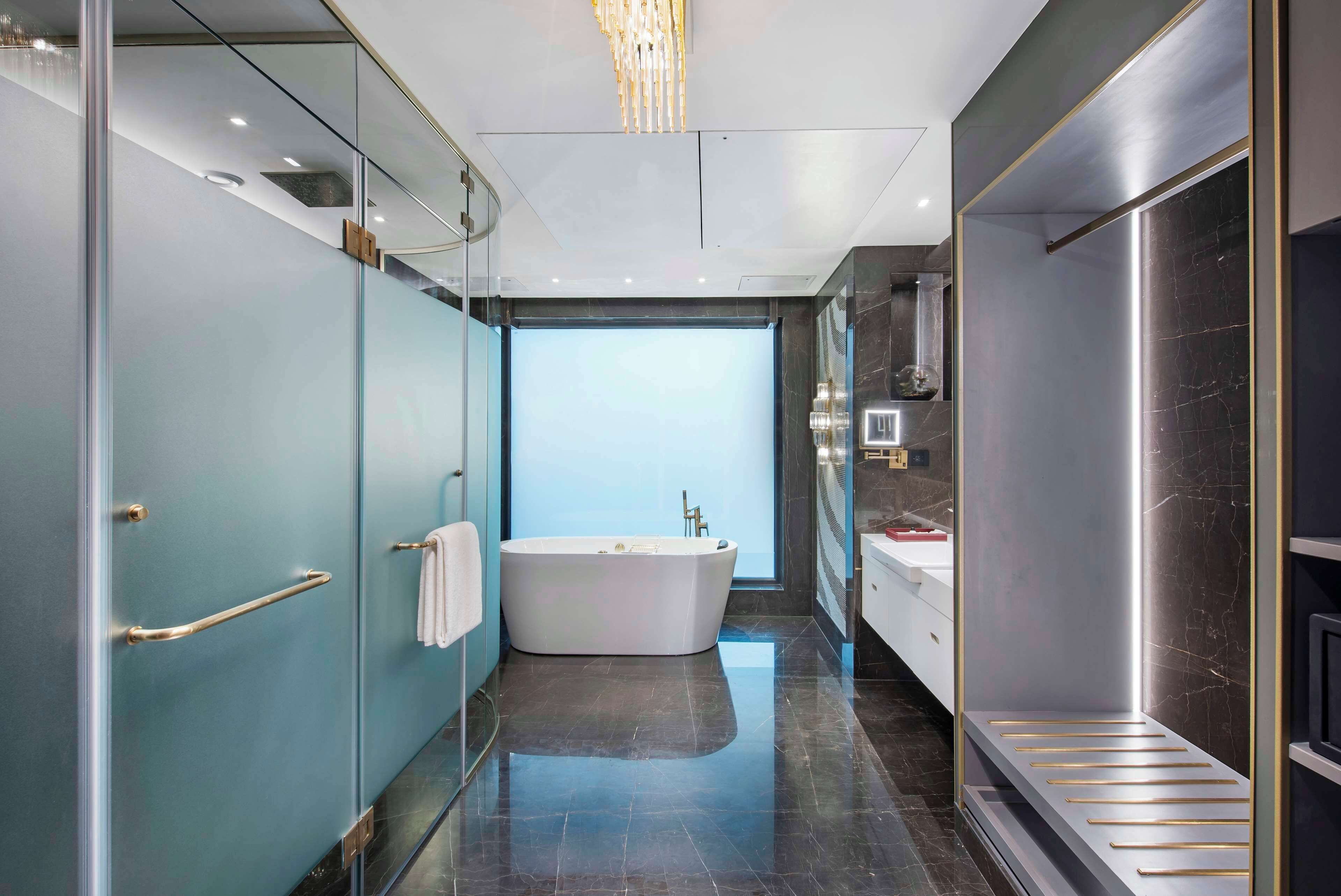 A modern bathroom with a freestanding bathtub, a glass shower enclosure, and a marble-topped vanity.