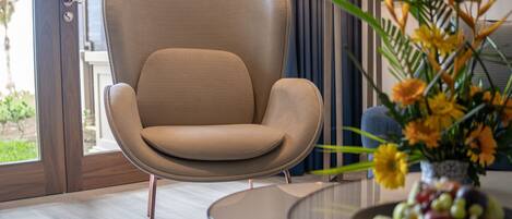 Una sala de estar moderna con un sillón color beige, una mesa de centro de vidrio y un arreglo floral.