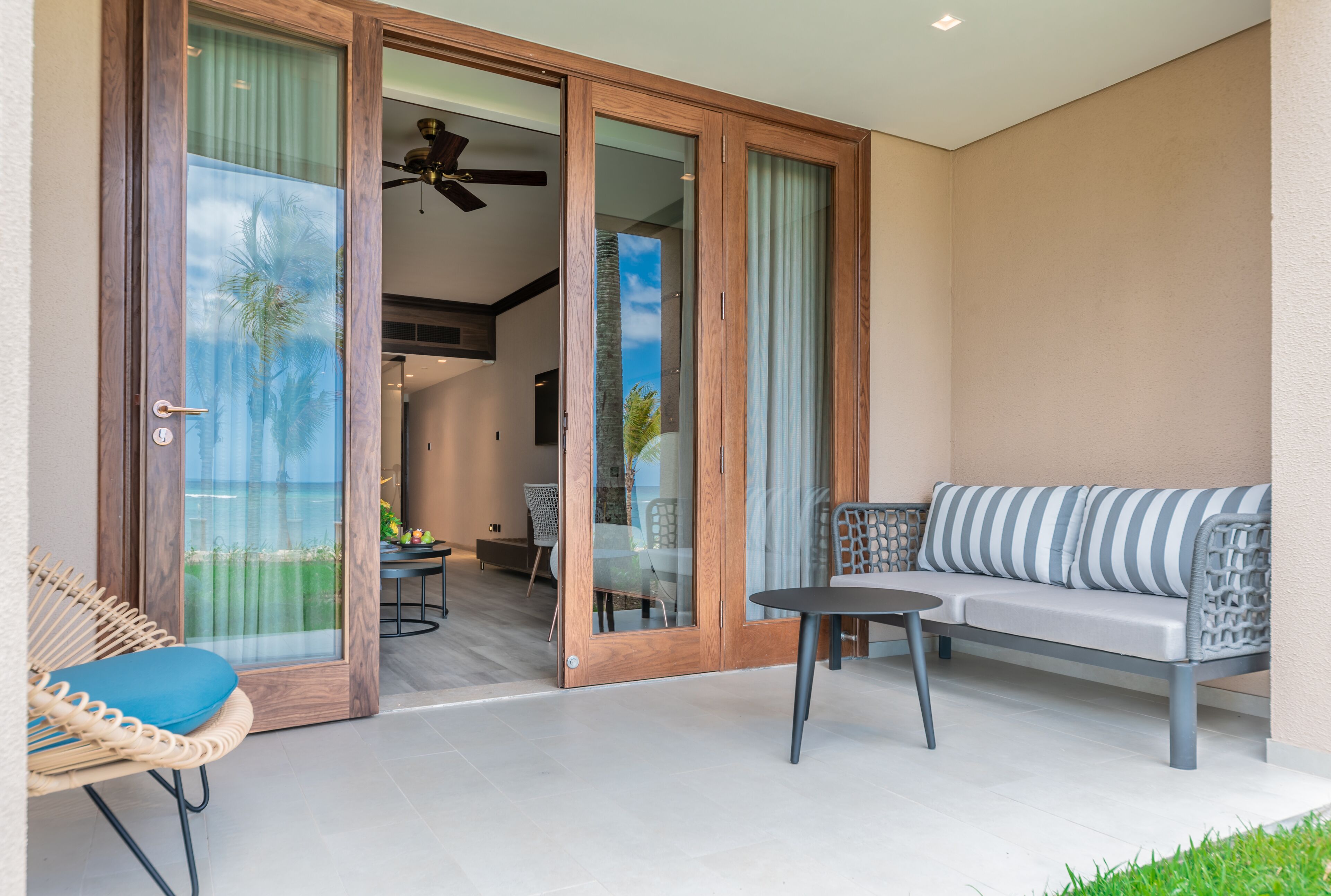 A modern outdoor seating area with a sofa and chairs, a table, and a glass door leading to an interior space.