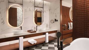 A modern bathroom with a large mirror, a white sink, and a wooden vanity.