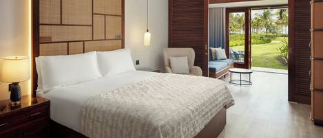 A hotel room with a large bed, a nightstand with a lamp, a chair, a small table, and a view of the outdoors.
