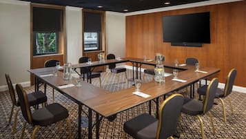 A conference room with a long table, chairs, and a television on the wall.