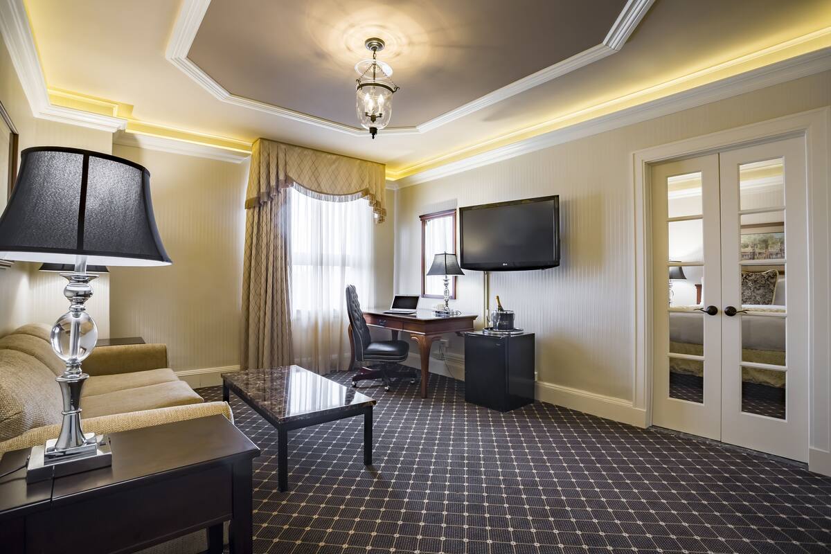 Ein Hotelzimmer mit Schreibtisch, Stuhl, Fernseher und Bett.