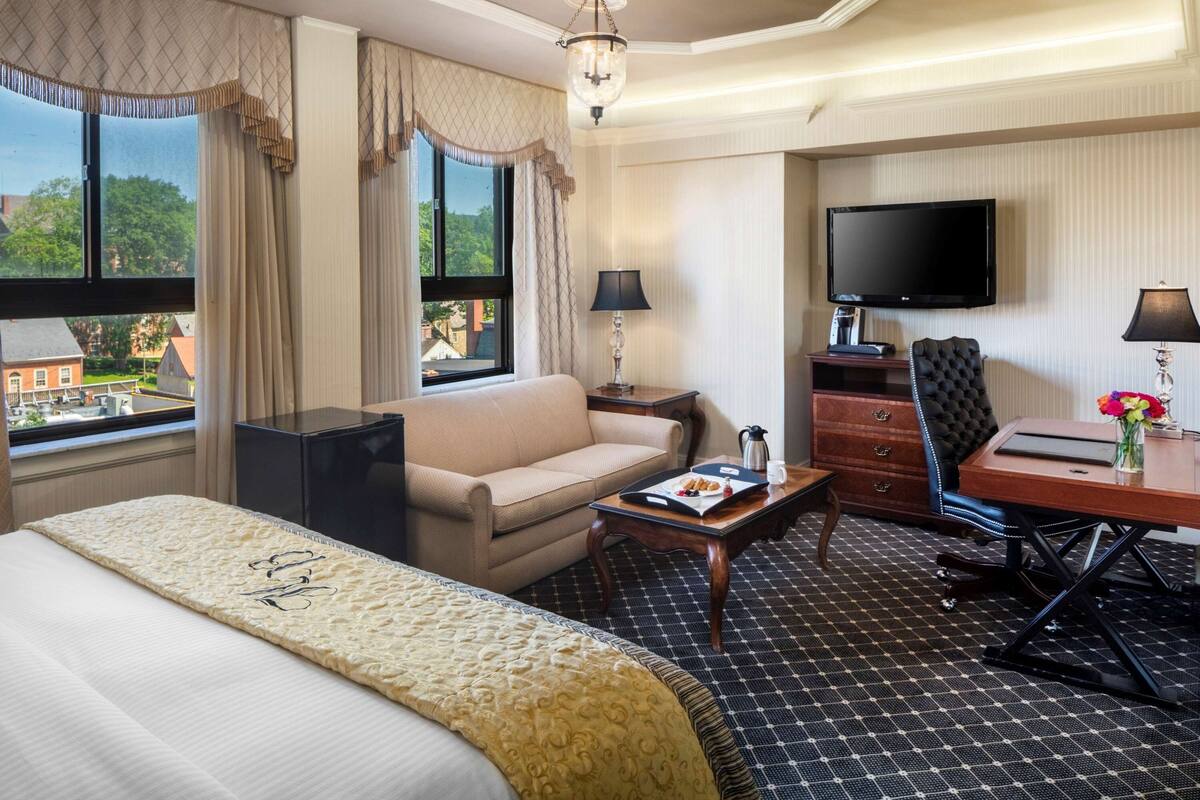Ein Hotelzimmer mit Bett, Sofa, Schreibtisch, Fernseher und Blick nach draußen.