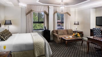 A hotel room with a bed, a sofa, a coffee table, a desk, and a TV.