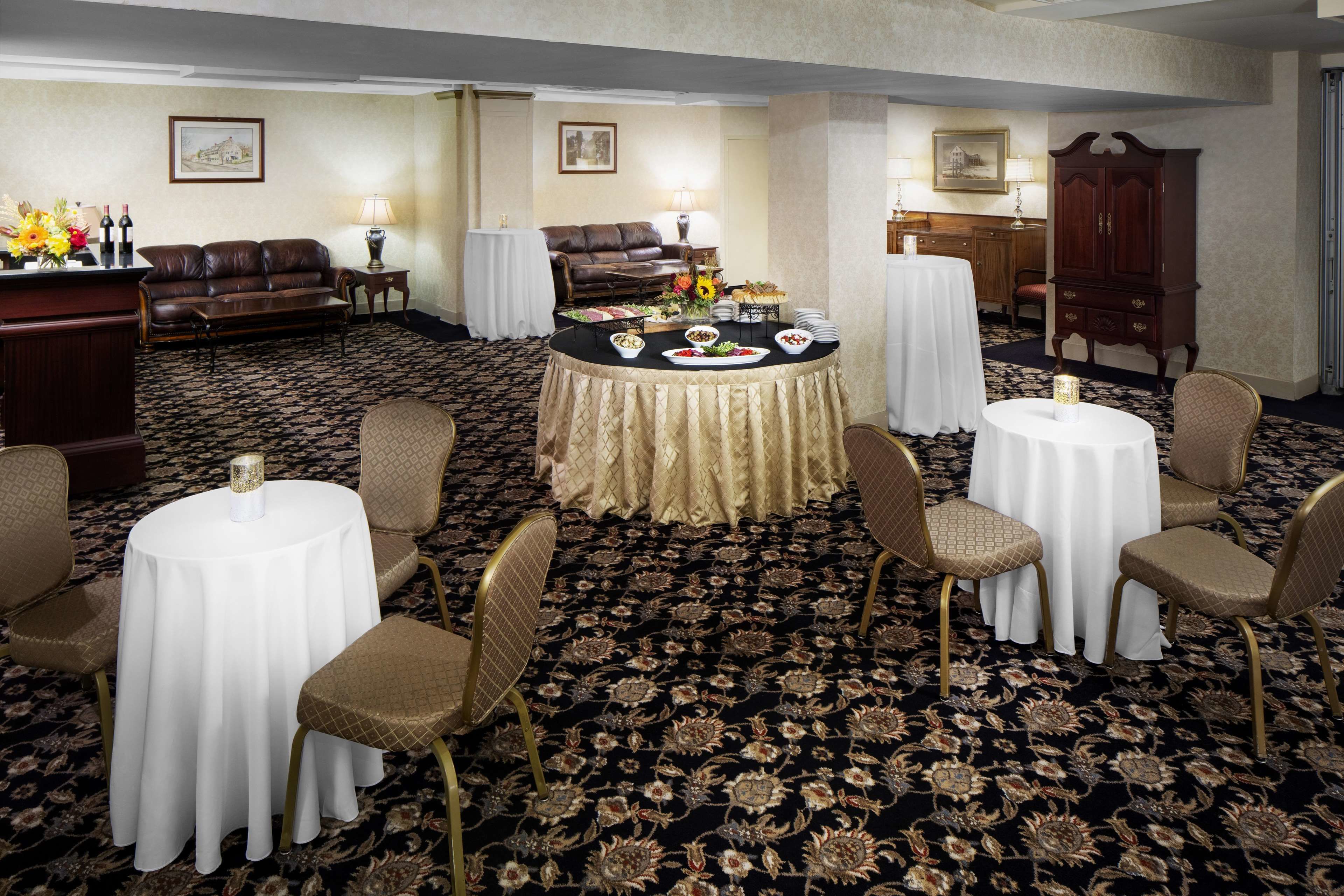 A hotel room with a round dining table, four chairs, a sofa, and a cabinet.