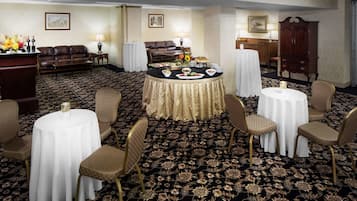 A hotel room with a round dining table, four chairs, a sofa, and a cabinet.