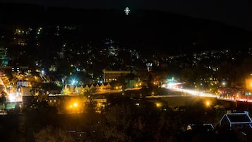 A nighttime view of a town with illuminated streets and buildings, a bridge, and a starry sky.