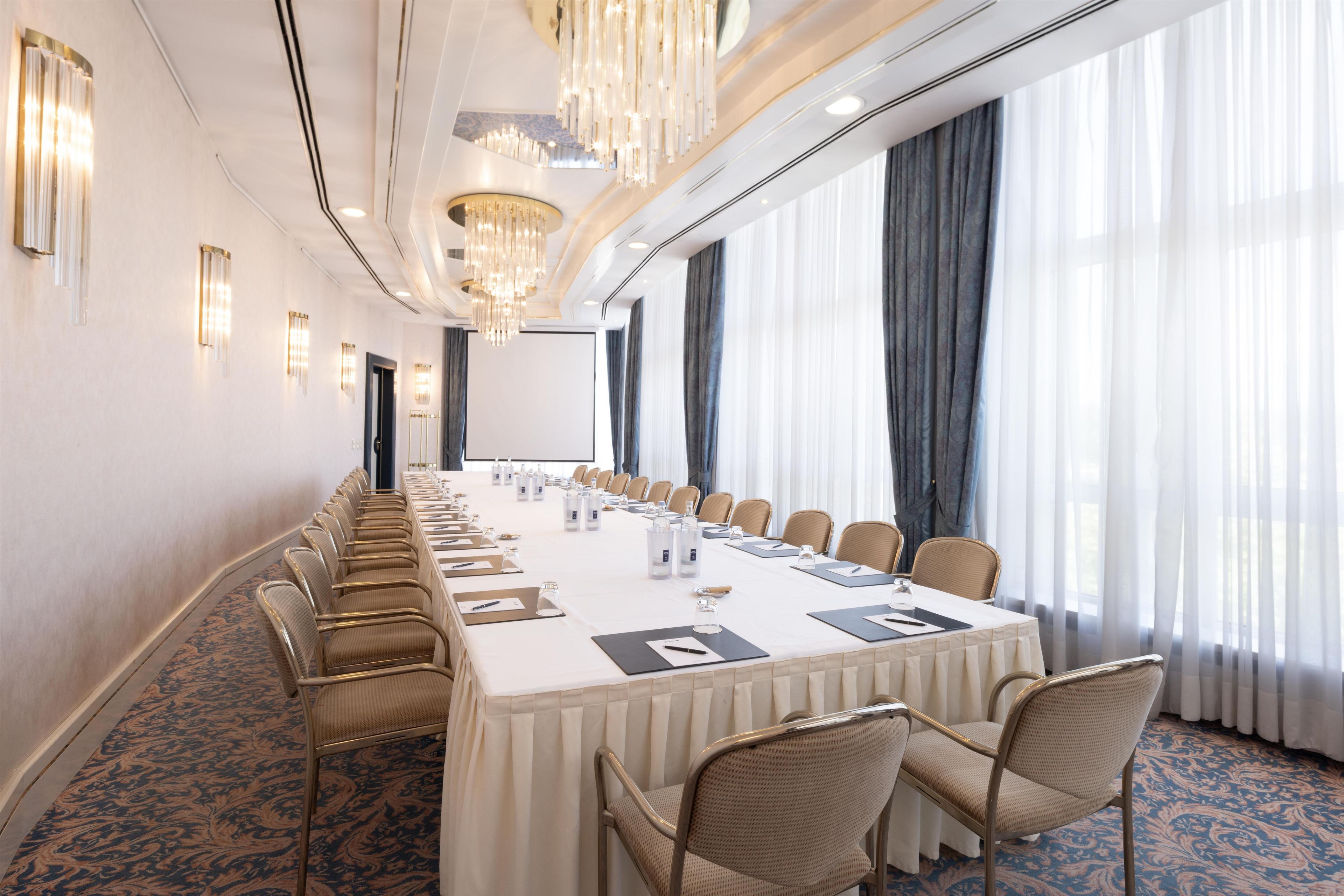Una sala conferenze con un lungo tavolo, sedie e un lampadario.