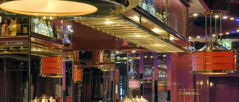 A bar area with multiple gold-colored dispensers, a variety of bottles, and a well-lit ambiance with overhead lighting fixtures.
