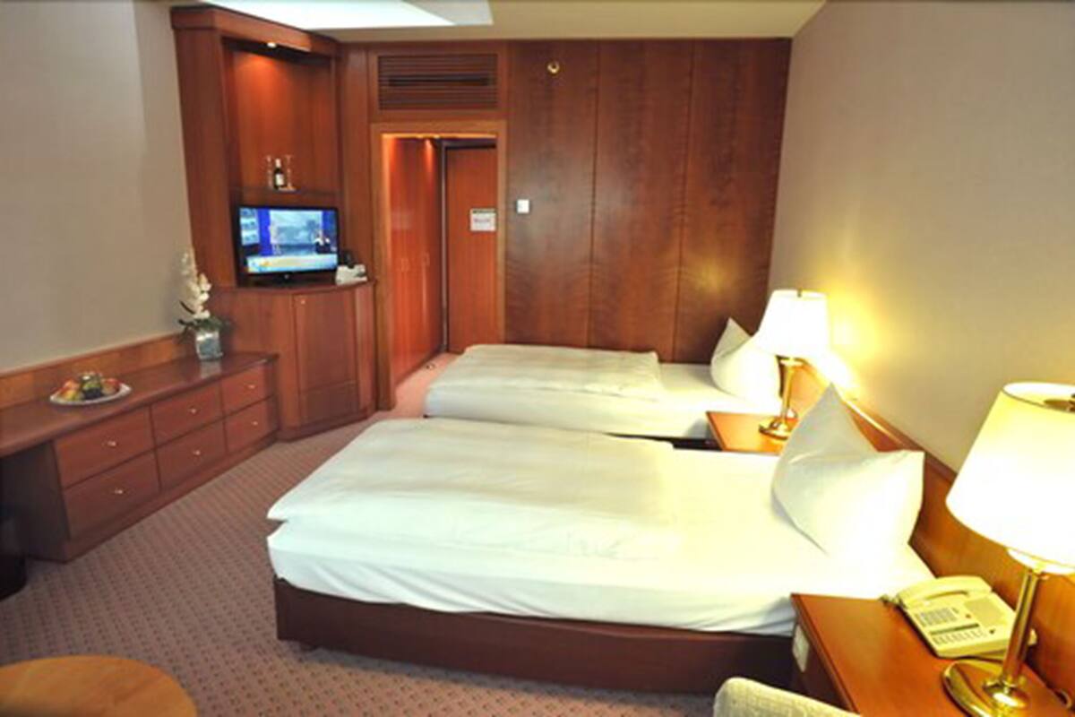 A hotel room with two beds, a TV, a desk with a lamp, and a telephone.