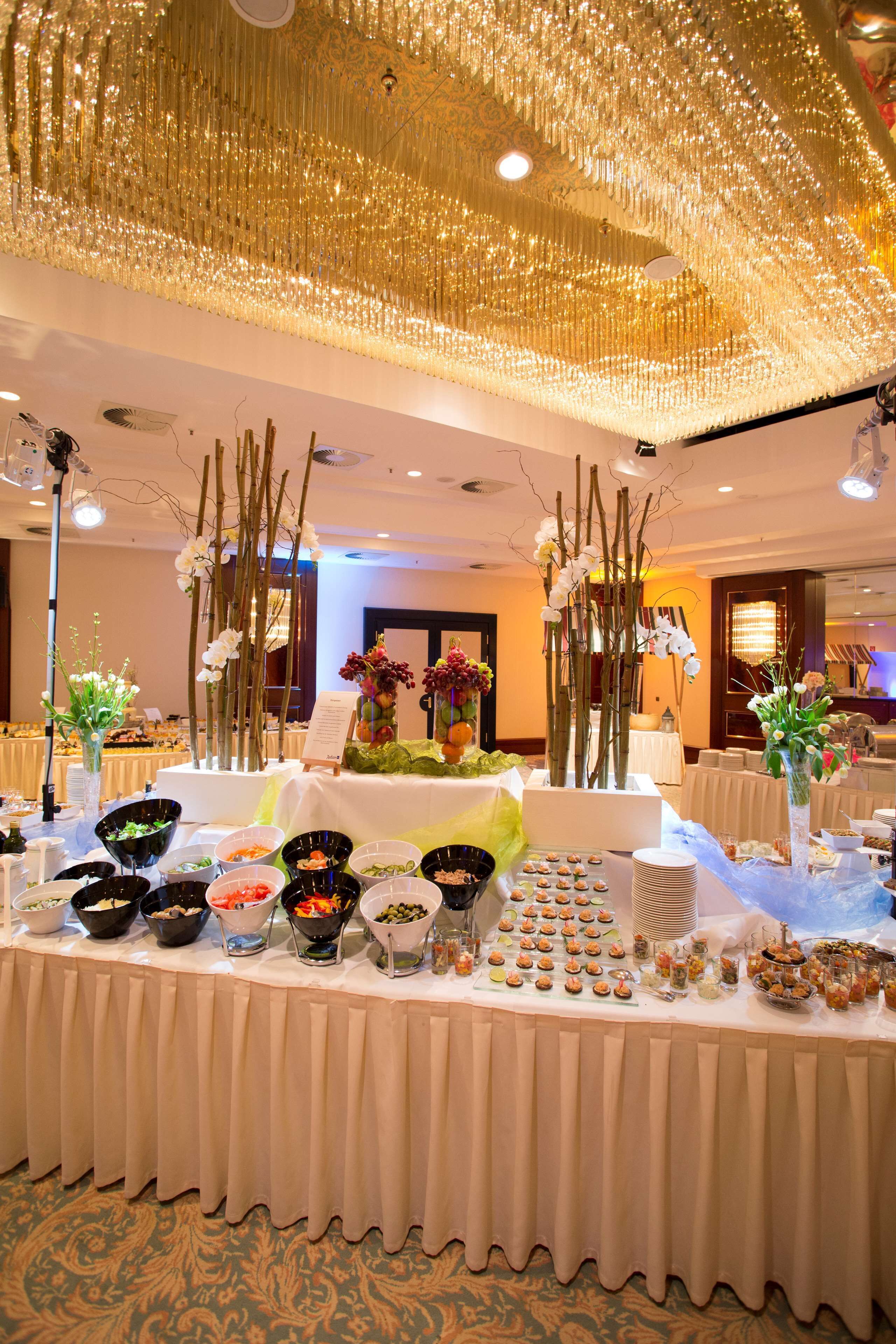 A buffet table with various food items and decorative elements like orchids and branches.